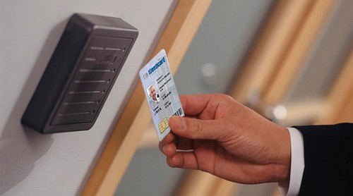 Image of an employee swiping a key card across the reader base next to a door.