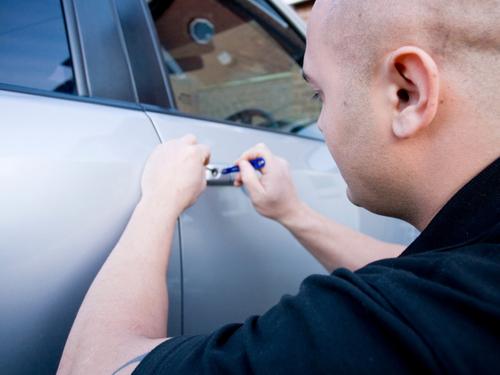One of our automotive locksmith technicians picking the lock on a car door.